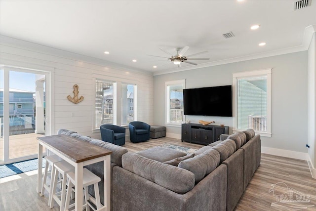 living room featuring plenty of natural light, ceiling fan, light wood-type flooring, and crown molding