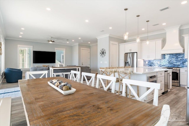 dining area with ceiling fan, light wood-type flooring, and ornamental molding