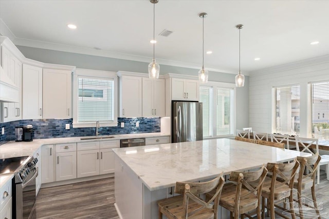 kitchen featuring appliances with stainless steel finishes, a kitchen island, plenty of natural light, and sink