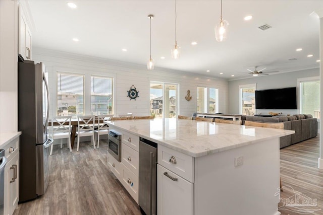 kitchen featuring white cabinets, decorative light fixtures, a center island, and stainless steel appliances