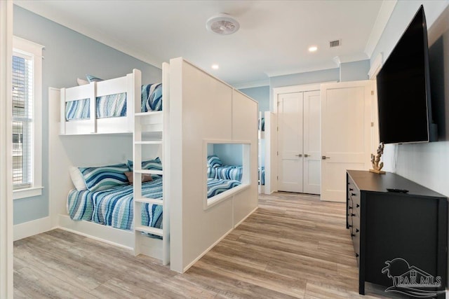 bedroom with light hardwood / wood-style floors, ornamental molding, a closet, and multiple windows