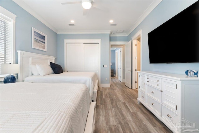 bedroom featuring ceiling fan, a closet, crown molding, and light wood-type flooring