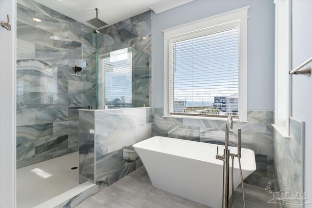 bathroom with tile patterned floors, plenty of natural light, separate shower and tub, and tile walls