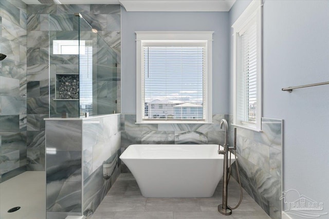 bathroom featuring tile patterned floors, independent shower and bath, tile walls, and a healthy amount of sunlight