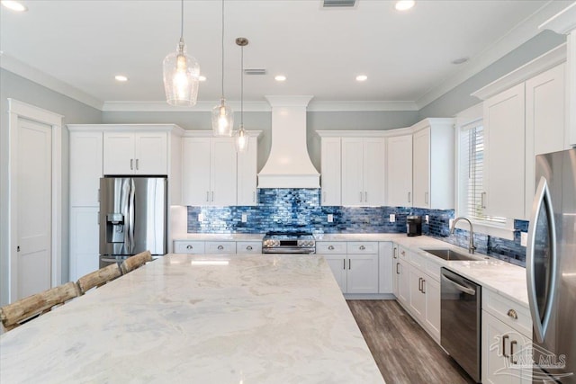 kitchen featuring light stone countertops, appliances with stainless steel finishes, custom exhaust hood, sink, and white cabinets