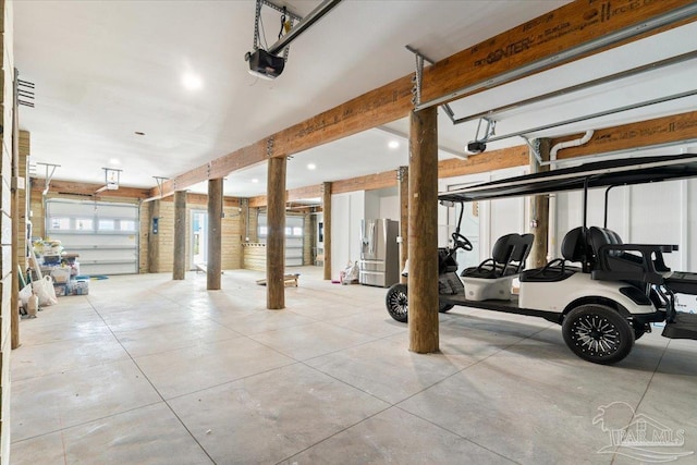 garage with stainless steel fridge with ice dispenser and a garage door opener