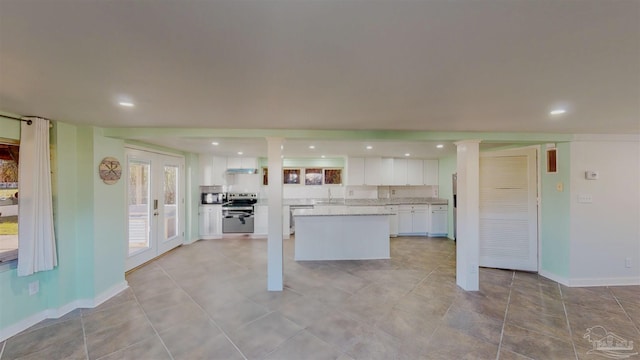 kitchen featuring stainless steel electric stove, light stone countertops, white cabinets, french doors, and sink