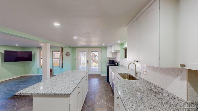 kitchen featuring light stone countertops, sink, and white cabinetry