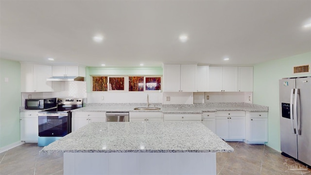 kitchen with appliances with stainless steel finishes, white cabinets, a kitchen island, light stone counters, and sink