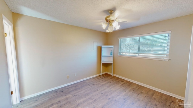 unfurnished room featuring ceiling fan, light wood-type flooring, and a textured ceiling