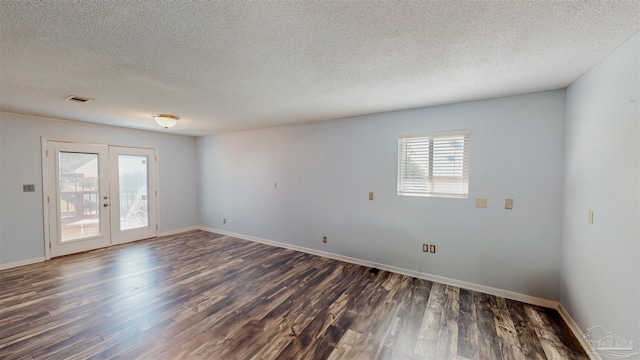 spare room featuring a textured ceiling, dark wood-type flooring, and french doors