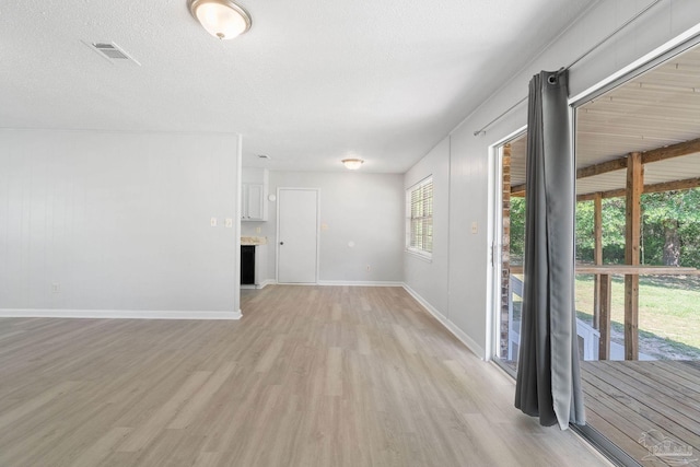 unfurnished living room with baseboards, light wood-style floors, and visible vents