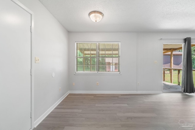 spare room with baseboards, wood finished floors, and a textured ceiling