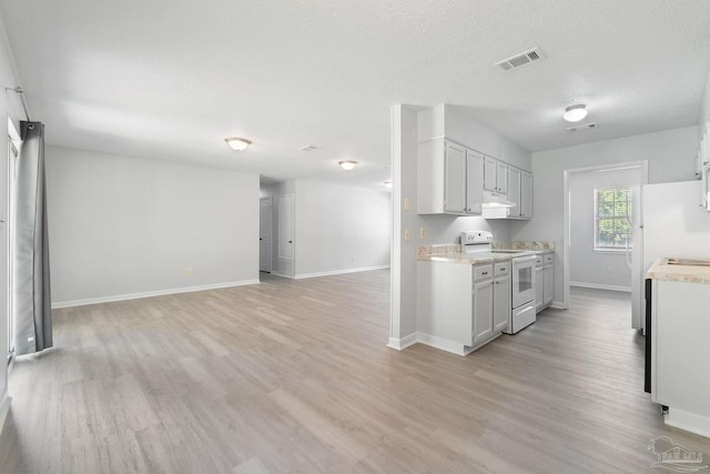 kitchen featuring light wood finished floors, light countertops, electric stove, visible vents, and baseboards