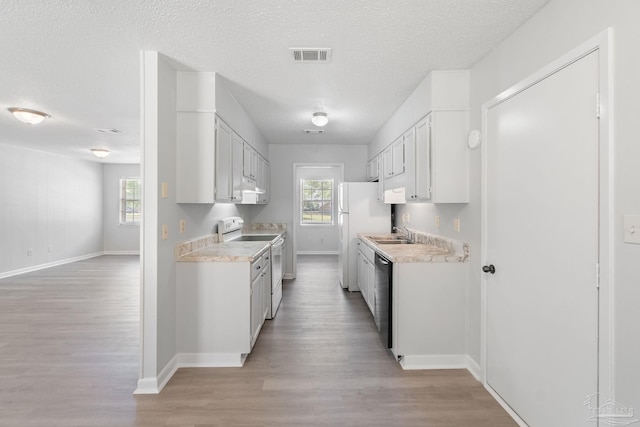 kitchen featuring white appliances, light wood-type flooring, light countertops, baseboards, and visible vents