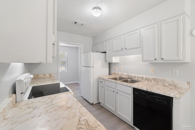 kitchen with a sink, freestanding refrigerator, visible vents, stove, and dishwasher
