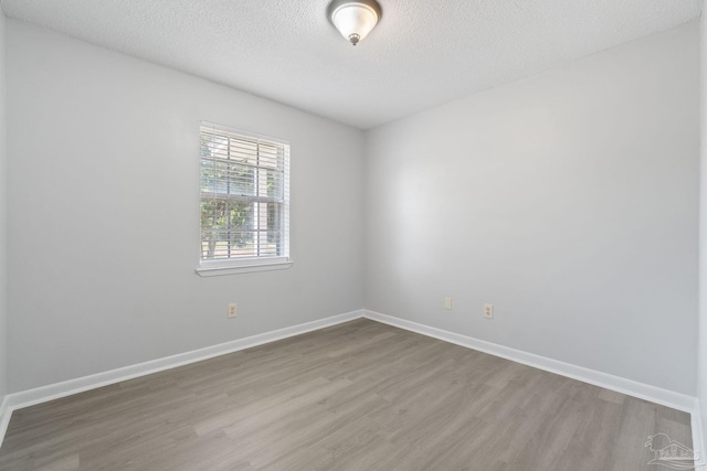 empty room featuring baseboards, wood finished floors, and a textured ceiling