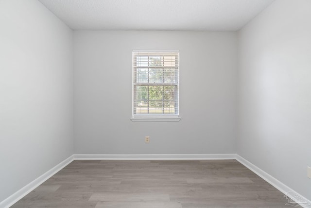 spare room featuring baseboards and wood finished floors