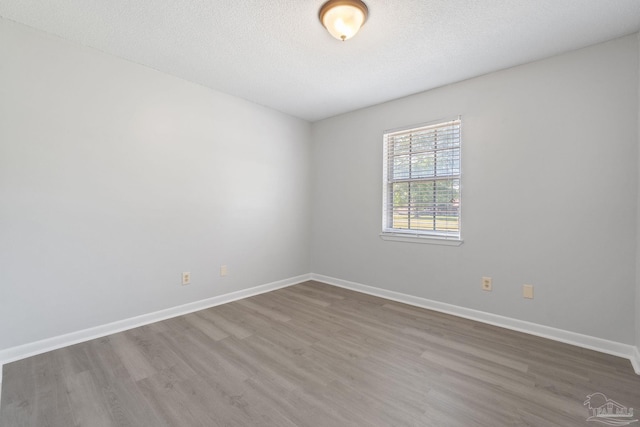unfurnished room featuring baseboards, wood finished floors, and a textured ceiling