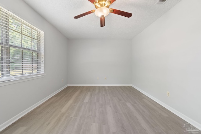 unfurnished room featuring baseboards, a ceiling fan, wood finished floors, and a textured ceiling