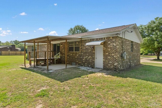 back of property with brick siding, a lawn, a patio, and fence