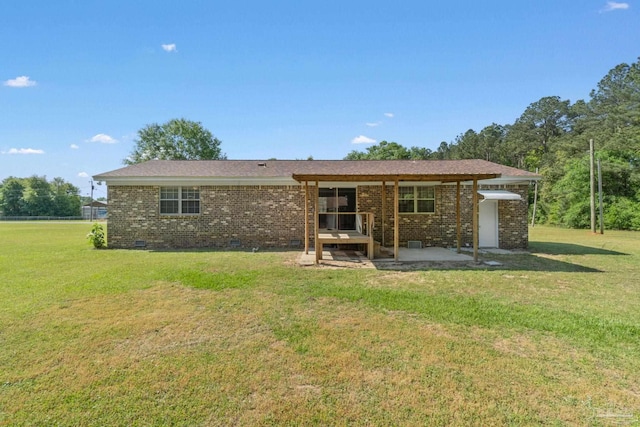 rear view of property featuring a yard, brick siding, a patio area, and crawl space
