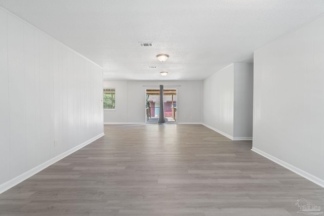 unfurnished room featuring baseboards, wood finished floors, visible vents, and a textured ceiling
