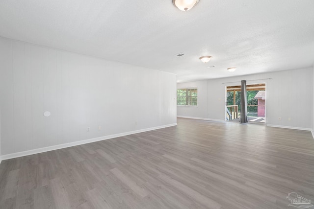 empty room with baseboards, wood finished floors, and a textured ceiling