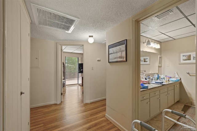corridor featuring baseboards, visible vents, and light wood-style flooring