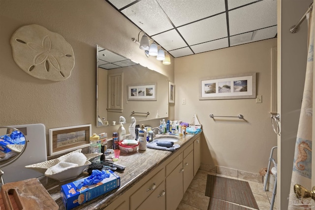 bathroom featuring baseboards, vanity, tile patterned floors, and a drop ceiling
