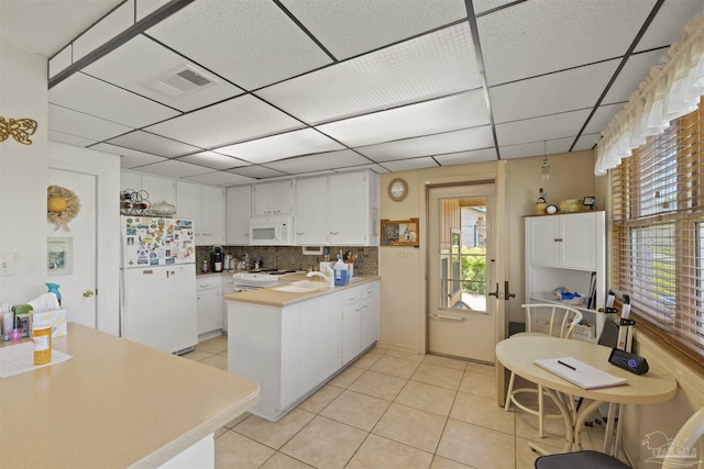 kitchen featuring light tile patterned flooring, white appliances, white cabinets, a peninsula, and visible vents