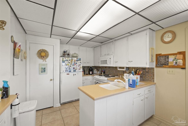 kitchen with a peninsula, light countertops, white appliances, and light tile patterned floors