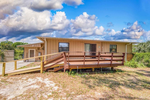 rear view of property with board and batten siding and a deck