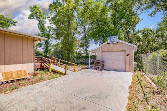 view of home's exterior featuring an outdoor structure, a detached garage, concrete driveway, and fence