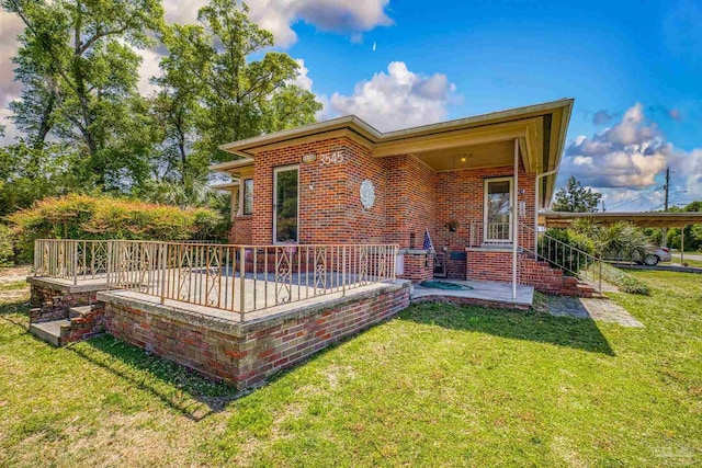 back of property with brick siding and a yard