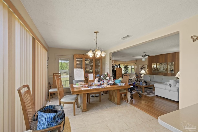 dining room with ceiling fan with notable chandelier, visible vents, a textured ceiling, and light tile patterned flooring