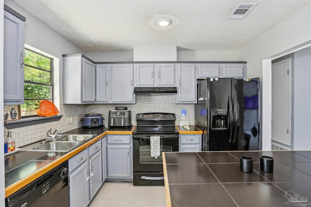 kitchen with under cabinet range hood, visible vents, a sink, black appliances, and a textured ceiling