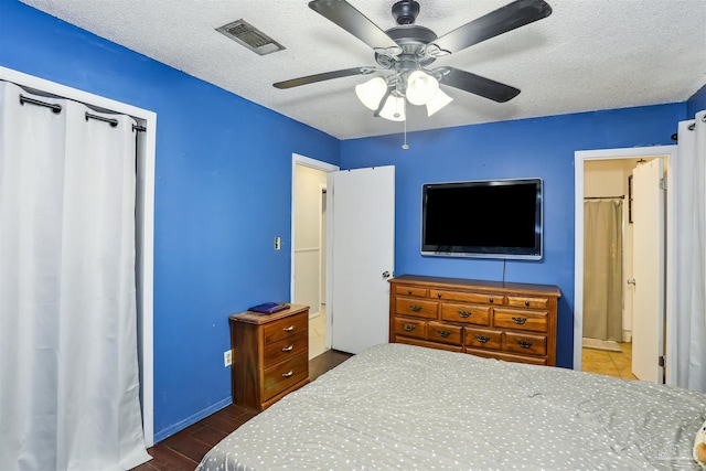 bedroom with a ceiling fan, visible vents, a textured ceiling, and dark wood-type flooring