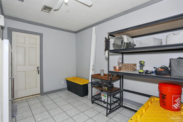 interior space with a textured ceiling, light tile patterned floors, ceiling fan, and visible vents