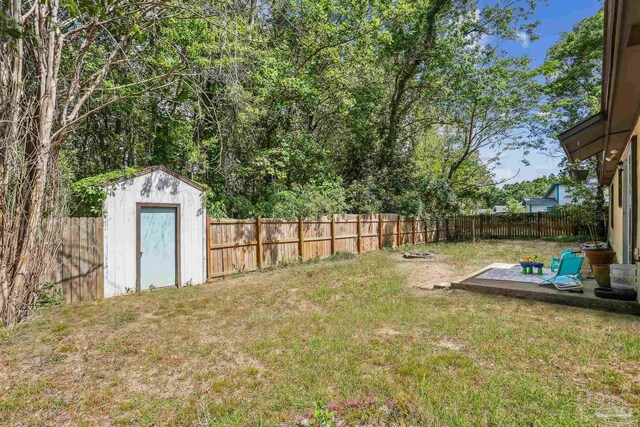 view of yard featuring a fenced backyard, an outdoor structure, and a shed