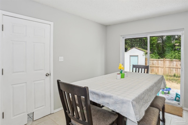 dining room featuring baseboards, a textured ceiling, and light tile patterned floors