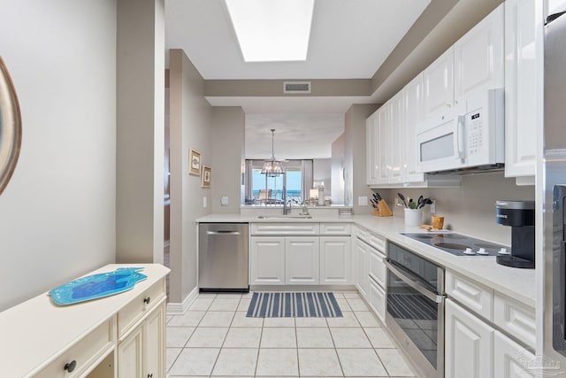 kitchen featuring light tile patterned flooring, appliances with stainless steel finishes, decorative light fixtures, white cabinetry, and sink