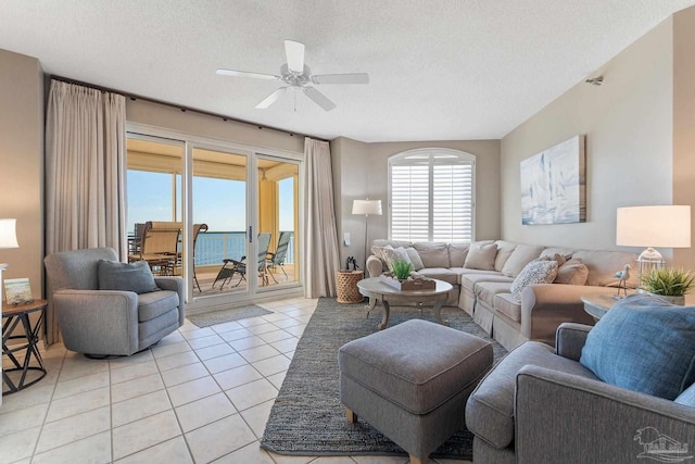 tiled living room with a water view, ceiling fan, and a textured ceiling