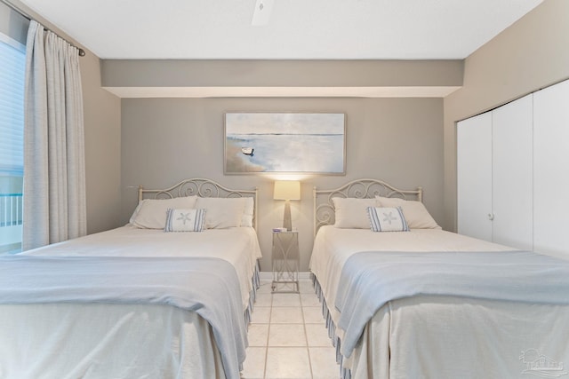 bedroom featuring light tile patterned floors, ceiling fan, and a closet