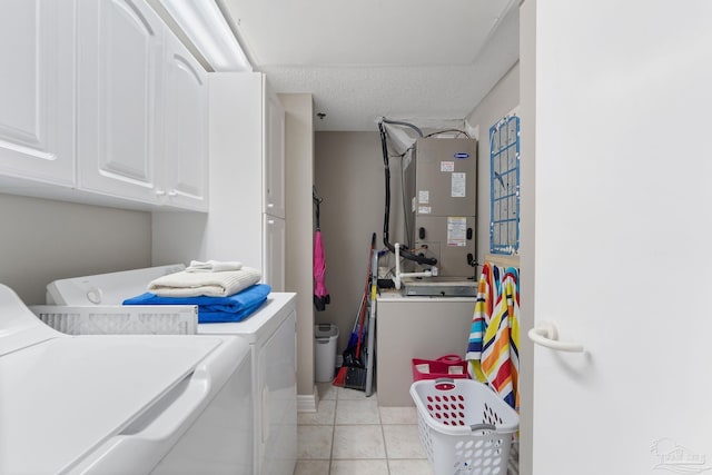 laundry area featuring heating unit, cabinets, light tile patterned floors, washing machine and clothes dryer, and a textured ceiling