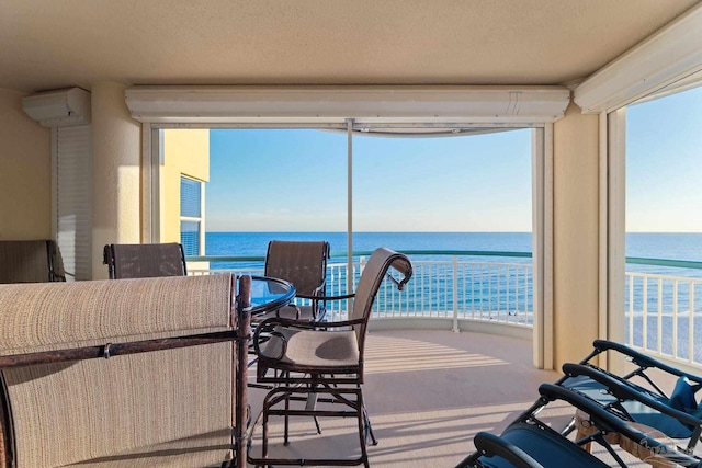 sunroom / solarium with a wealth of natural light, a water view, and a wall mounted AC