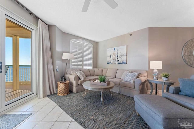 living room with a water view, ceiling fan, a textured ceiling, and light tile patterned floors