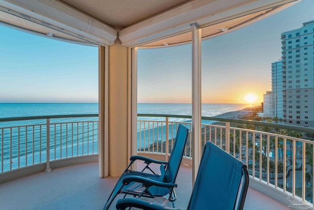 balcony at dusk with a beach view and a water view