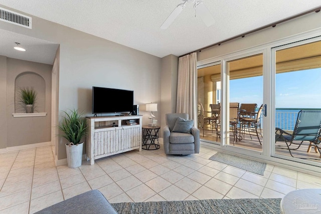 tiled living room with ceiling fan and a textured ceiling