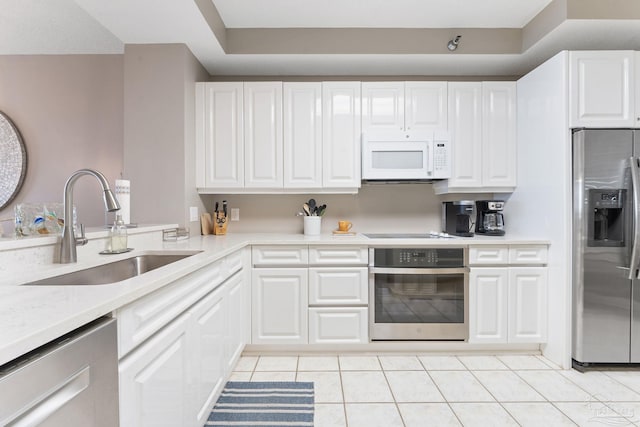 kitchen with light tile patterned flooring, appliances with stainless steel finishes, sink, and white cabinets